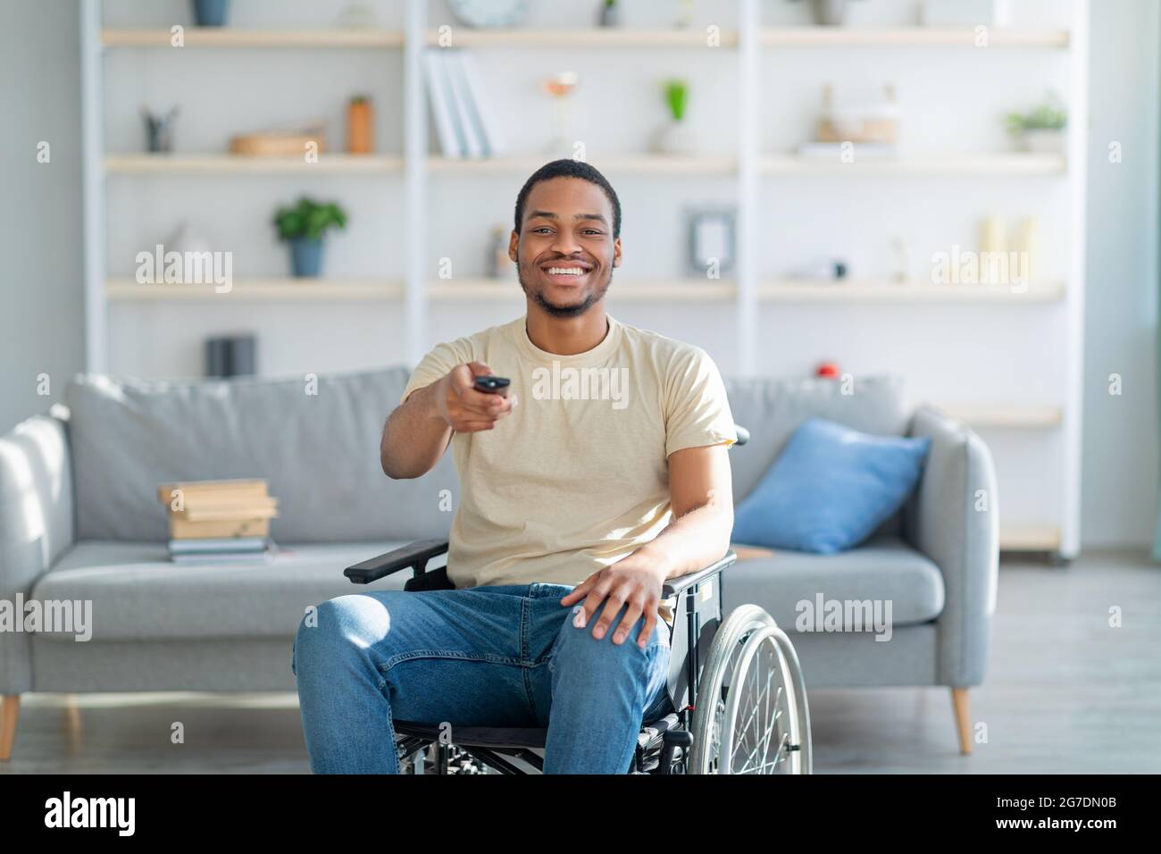 Home entertainments. Happy disabled African American guy with TV controller  enjoying movie indoors Stock Photo - Alamy