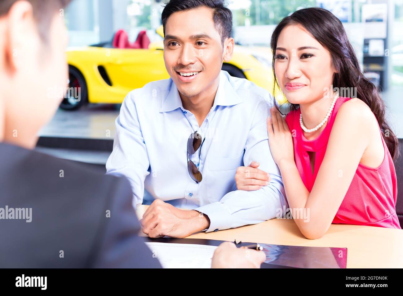 Asian Couple signing sales contract for car at dealership Stock Photo