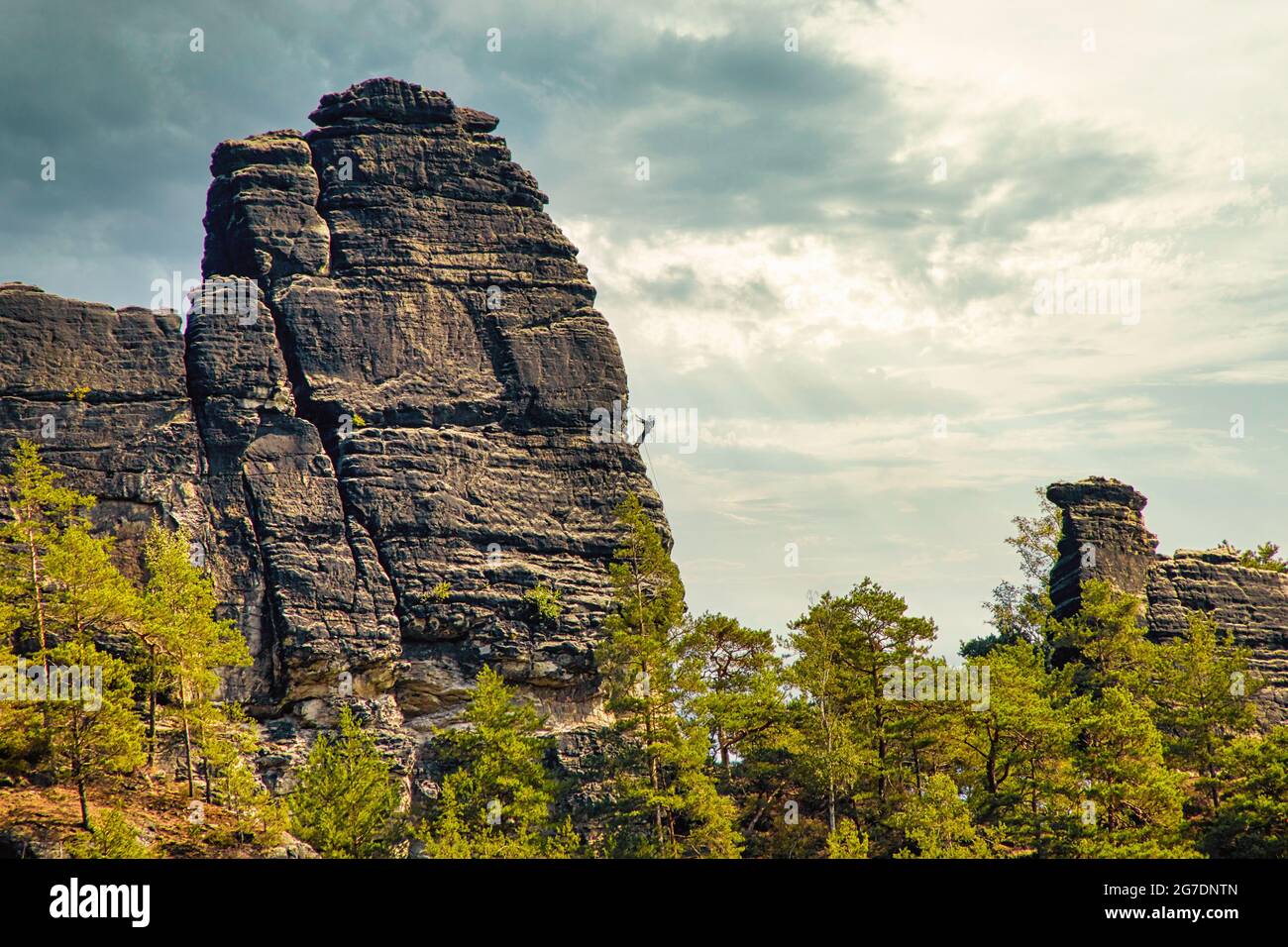 Sandstone rock formation the locomotive in German-Saxon Switzerland in the Elbe Sandstone Mountains with a climber on the right under a dramatic cloud Stock Photo