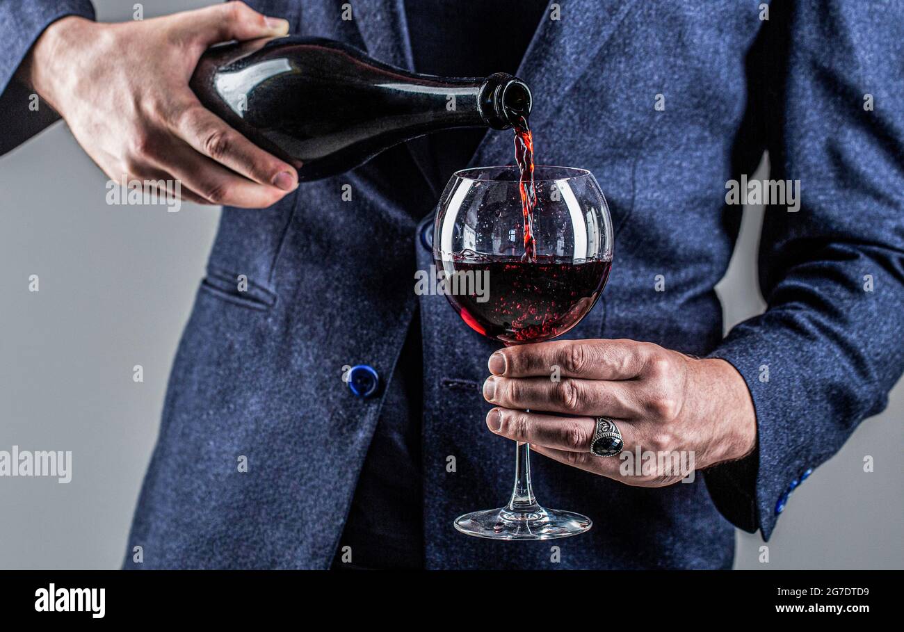 Waiter pouring red wine in a glass. Sommelier man, degustation, winery, male winemaker. Red wine is poured from bottle to glass. Gourmet drink bottle Stock Photo