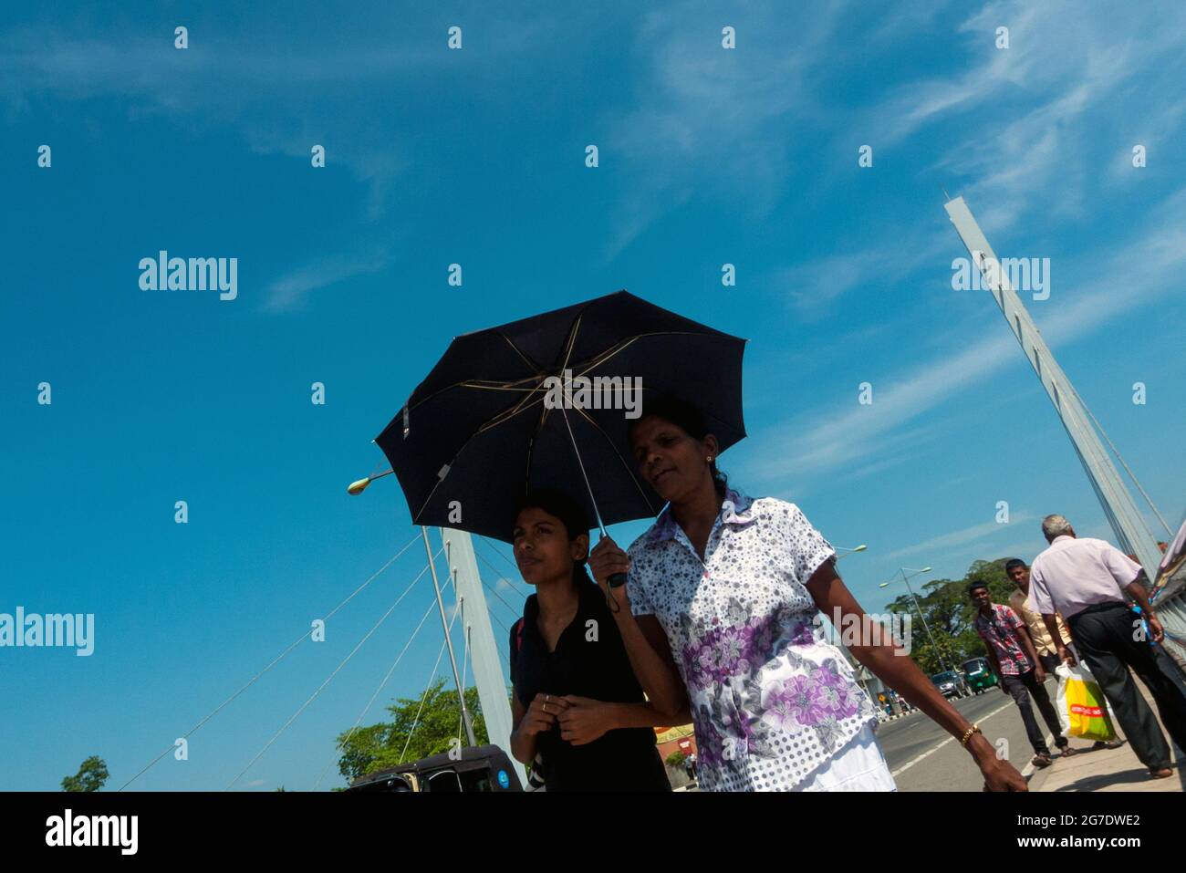 Matara, Sri Lanka, Asia: young women shelter from the sun with umbrellas while walking Stock Photo