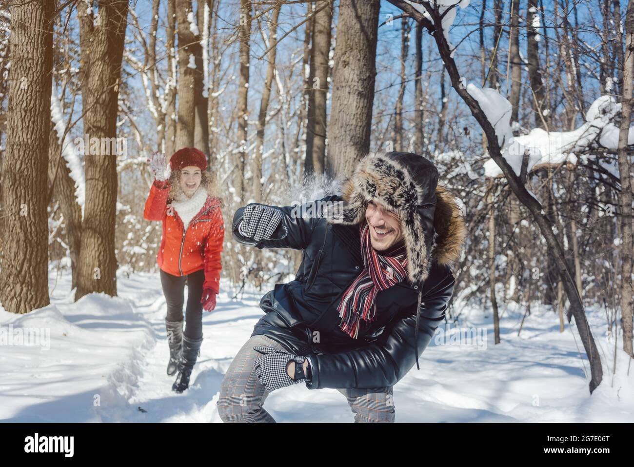 Woman throwing snowball on her guy in winter in playful mood teasing him Stock Photo