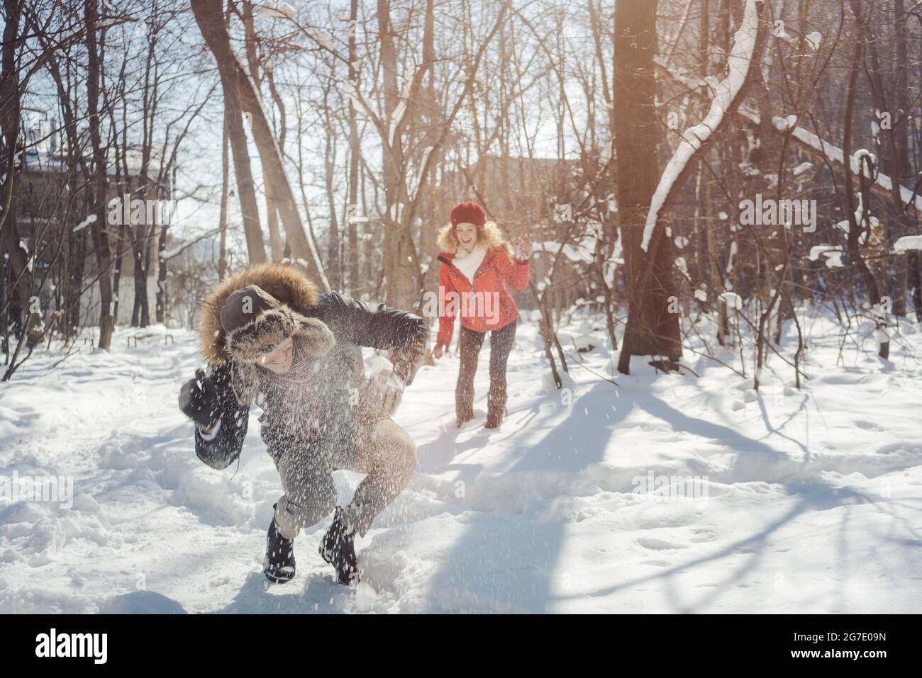 Woman throwing snowball on her guy in winter in playful mood teasing him Stock Photo