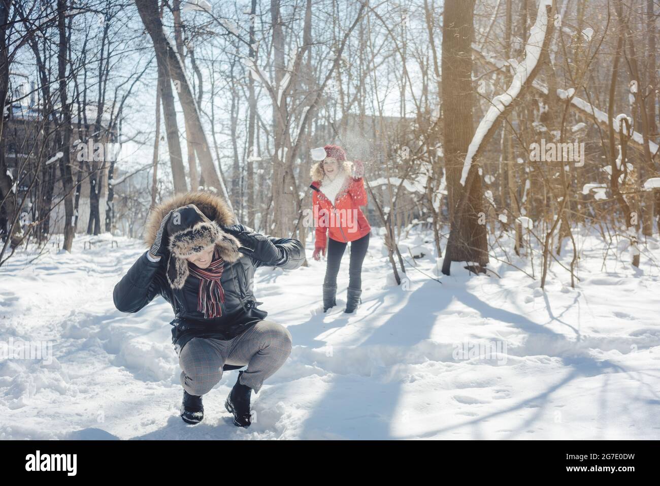 Woman throwing snowball on her guy in winter in playful mood teasing him Stock Photo