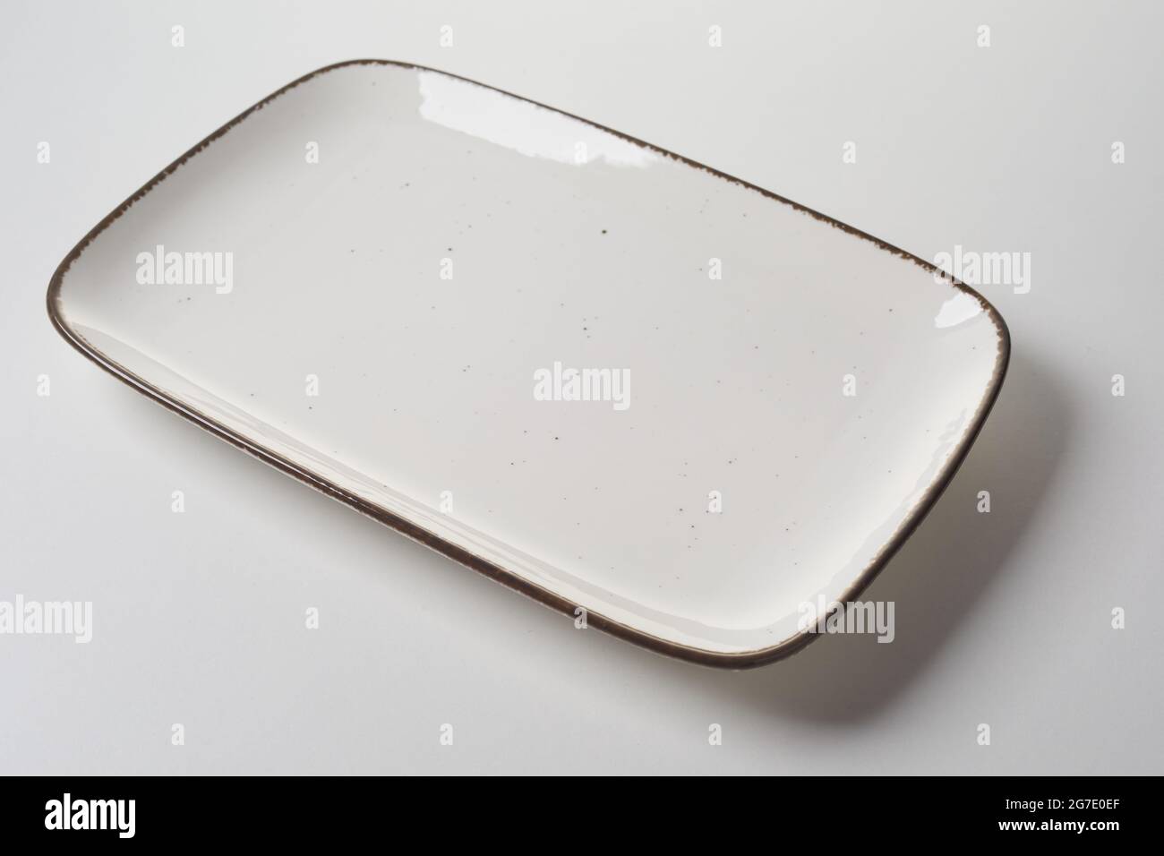 Large rectangular ceramic platter with dark rim for placement of meat for menu advertising in a diagonal high angle view on a white studio background Stock Photo