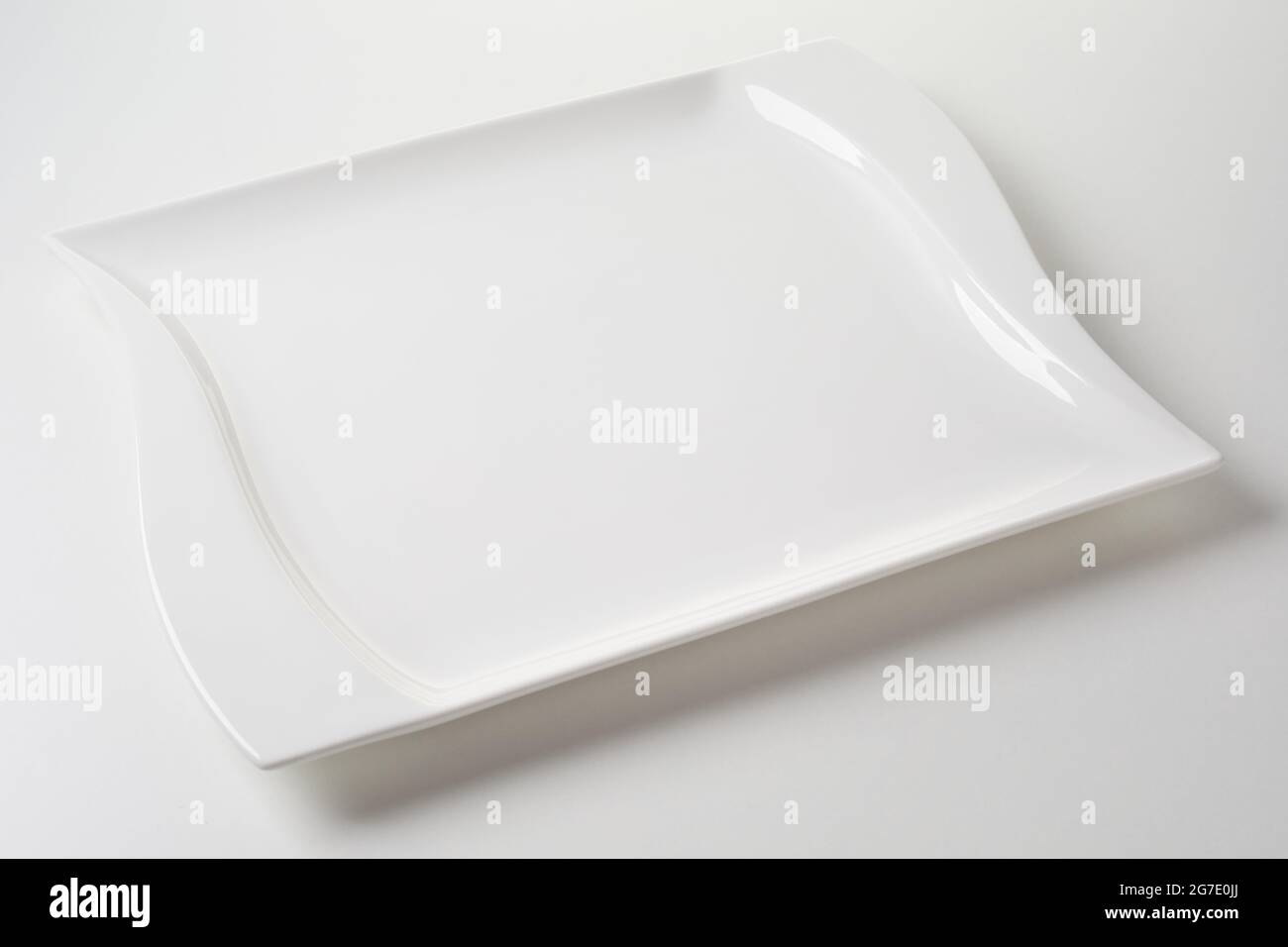 Elegant modern wavy or curving empty clean white rectangular dinner plate for food a placement template for advertising on a white studio background i Stock Photo