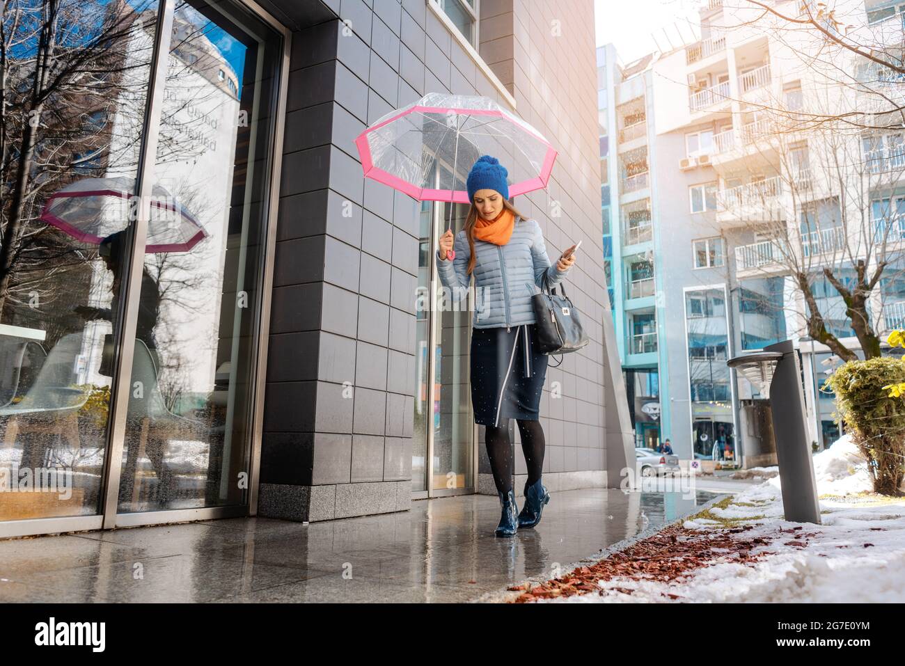 Woman walking through the puddles of the city in pre-spring Stock Photo