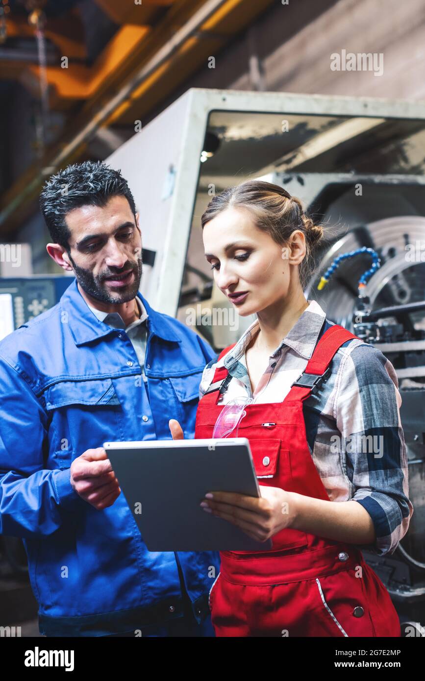 Woman and man manufacturing worker in discussion writing on tablet computer Stock Photo