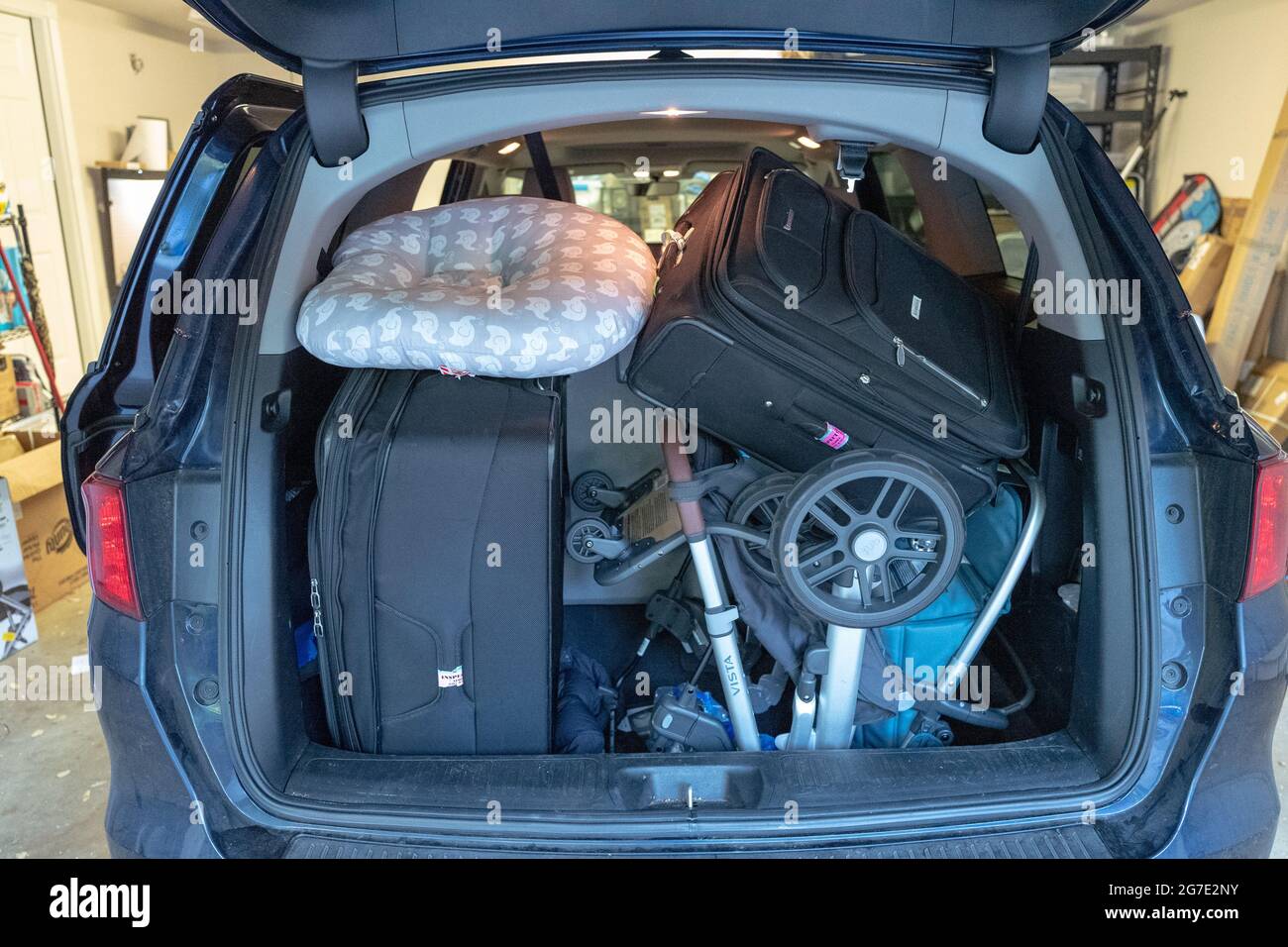 Rear view of open trunk of a minivan in suburban garage packed fully with suitcases and a stroller in preparation for travel or a vacation, Lafayette, California, May 28, 2021. () Stock Photo