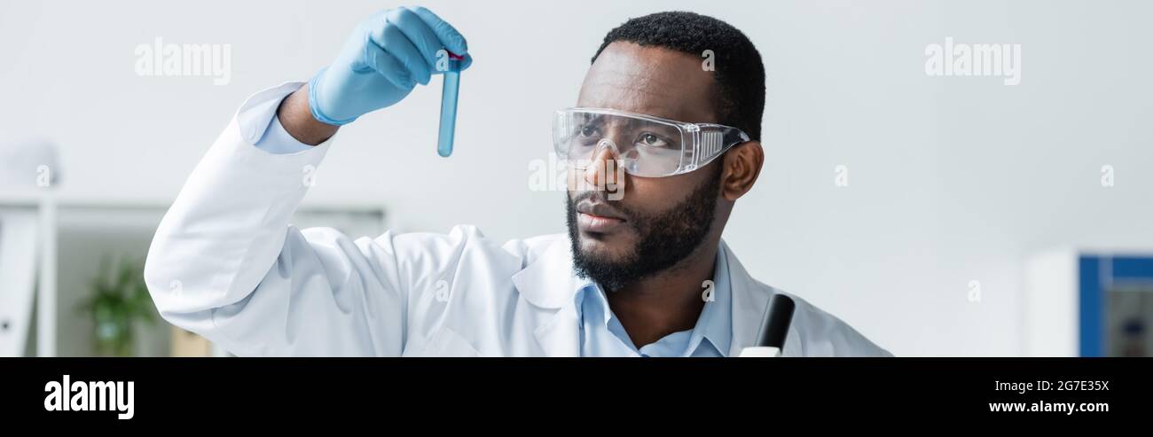 African american scientist in safety goggles holding test tube, banner Stock Photo