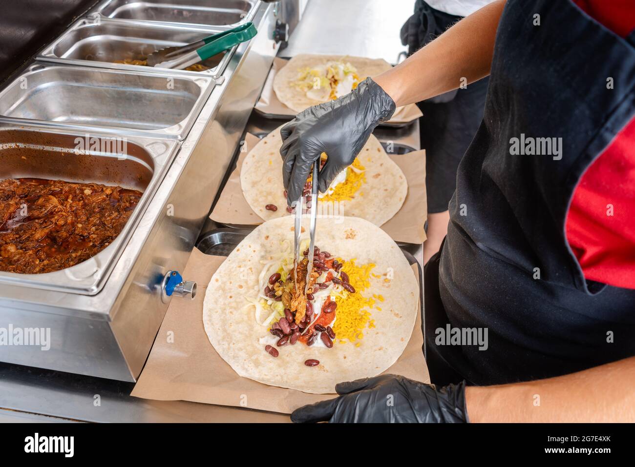 Woman preparing burrito in a food truck putting the ingredients in