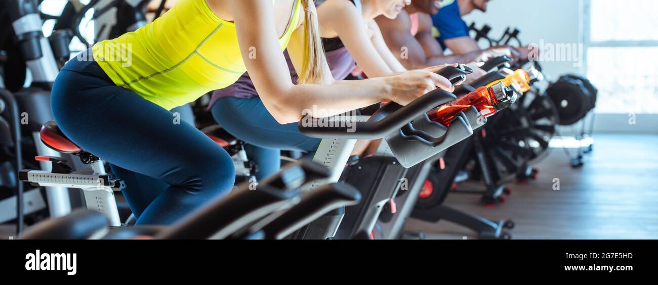 Very fit Caucasian woman and her friends on fitness bike in gym Stock Photo