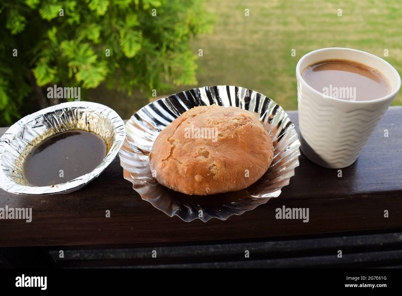 Indian breakfast Mung dal kachori snack item served with khajoor chutney and cup of tea.. Outdoors nature background on table balcony. Indian breakfas Stock Photo