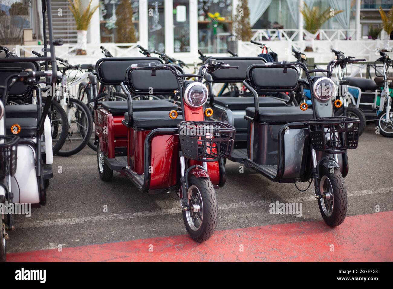 Moto electric vehicles are in a row. Electric bike rental. Headlights at two wheeled vehicles. Motorcycle sale. Mass parking of vehicles. Modern urban Stock Photo