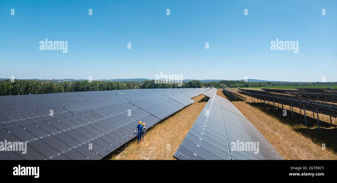 Large scale photovoltaic power plant with people standing at the panels Stock Photo