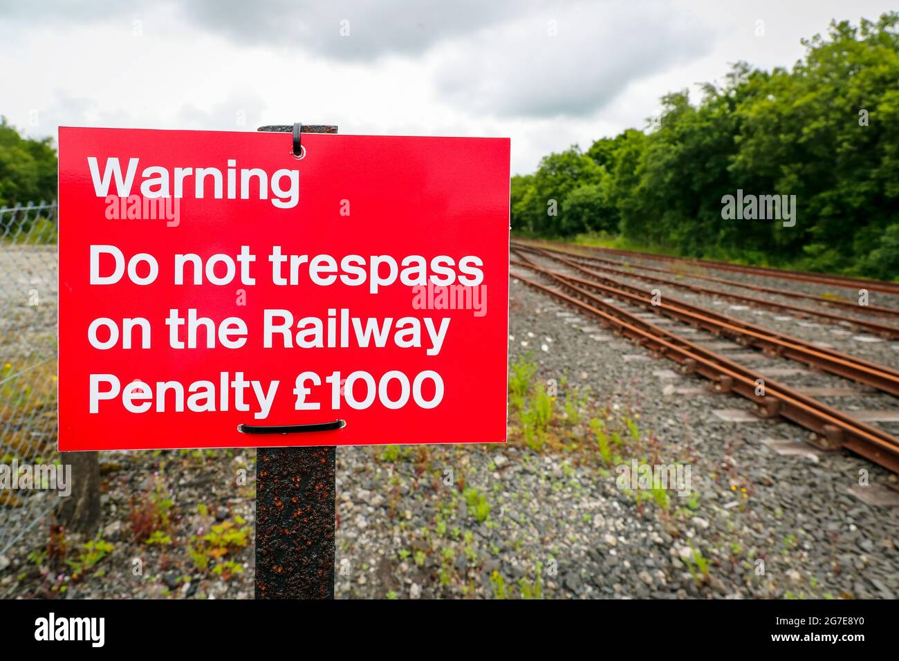 warning sign prohibiting trespass and financial penalty for walking on the railway lines. Stock Photo
