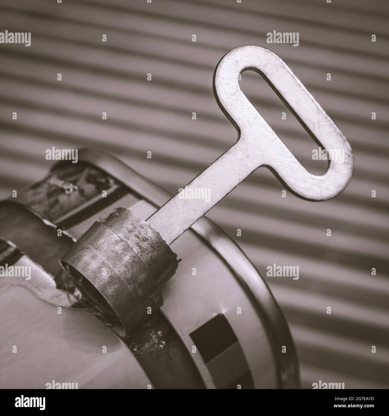 Monochrome twist-key tin opener / can-opener on an ASDA luncheon meat tinned product. Concept for food preservation, opening a can of worms. Stock Photo