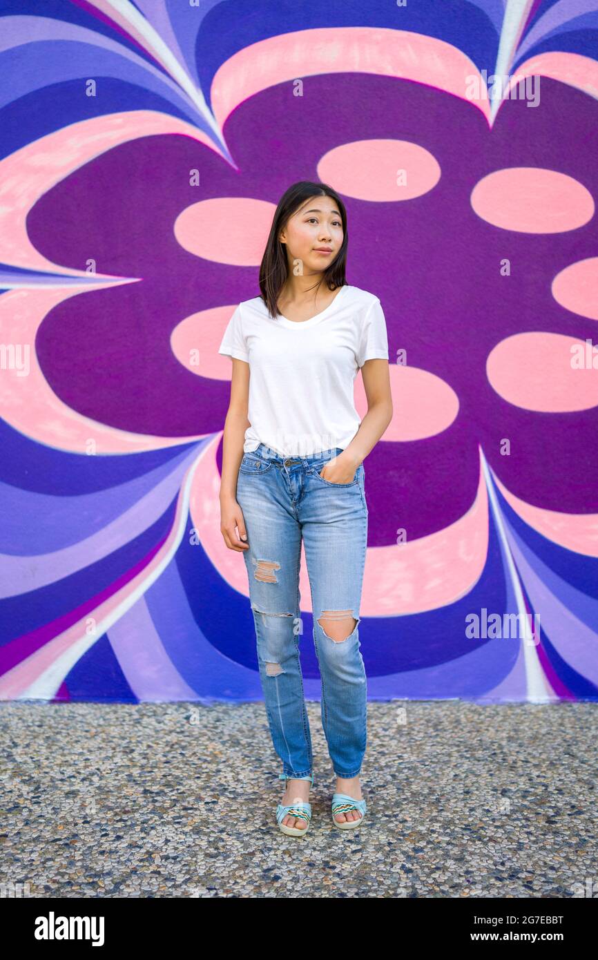 Young Asian Woman in 1960s Apparel Standing in Front of 1960s Style Mural Stock Photo