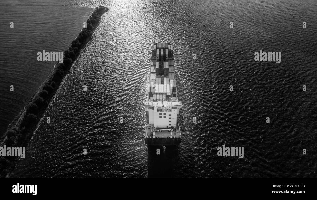Large full loaded container ship sailing sea near the coast. Aerial view, black and white hdr image Stock Photo