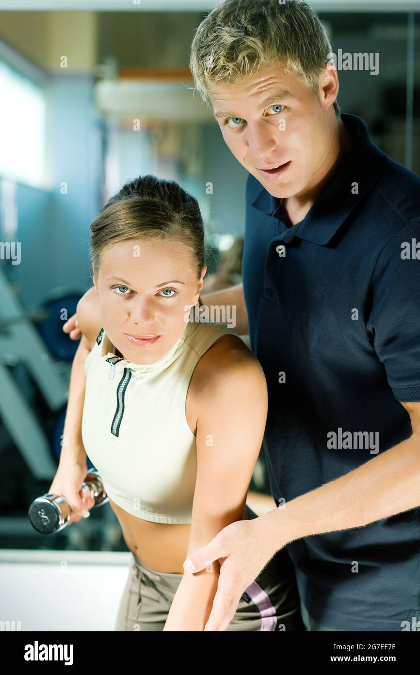 Trainer Instructing A Beautiful Woman In The Gym On How To Properly