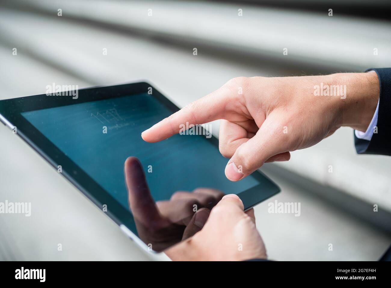 Businessman navigating on a tablet computer using his finger on the ...
