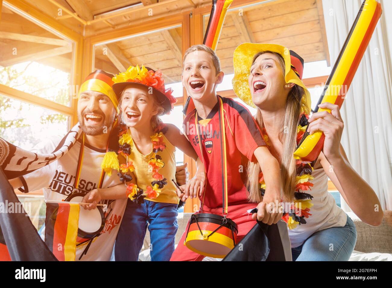 Whole family cheering for the German soccer team in front of TV at home Stock Photo