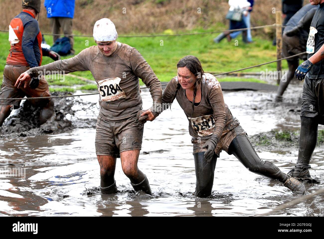 Tough Guy race near Wolverhampton 2005 competitors couple holding hands as they wade through freezing water. Britain Uk endurance physical running run exercise fitness Stock Photo