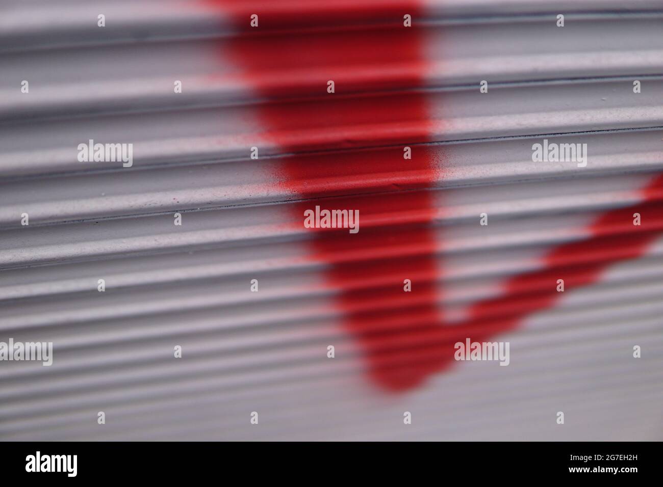 Closeup shot of an abstract white and red graffiti on a folding metal gate outdoors Stock Photo