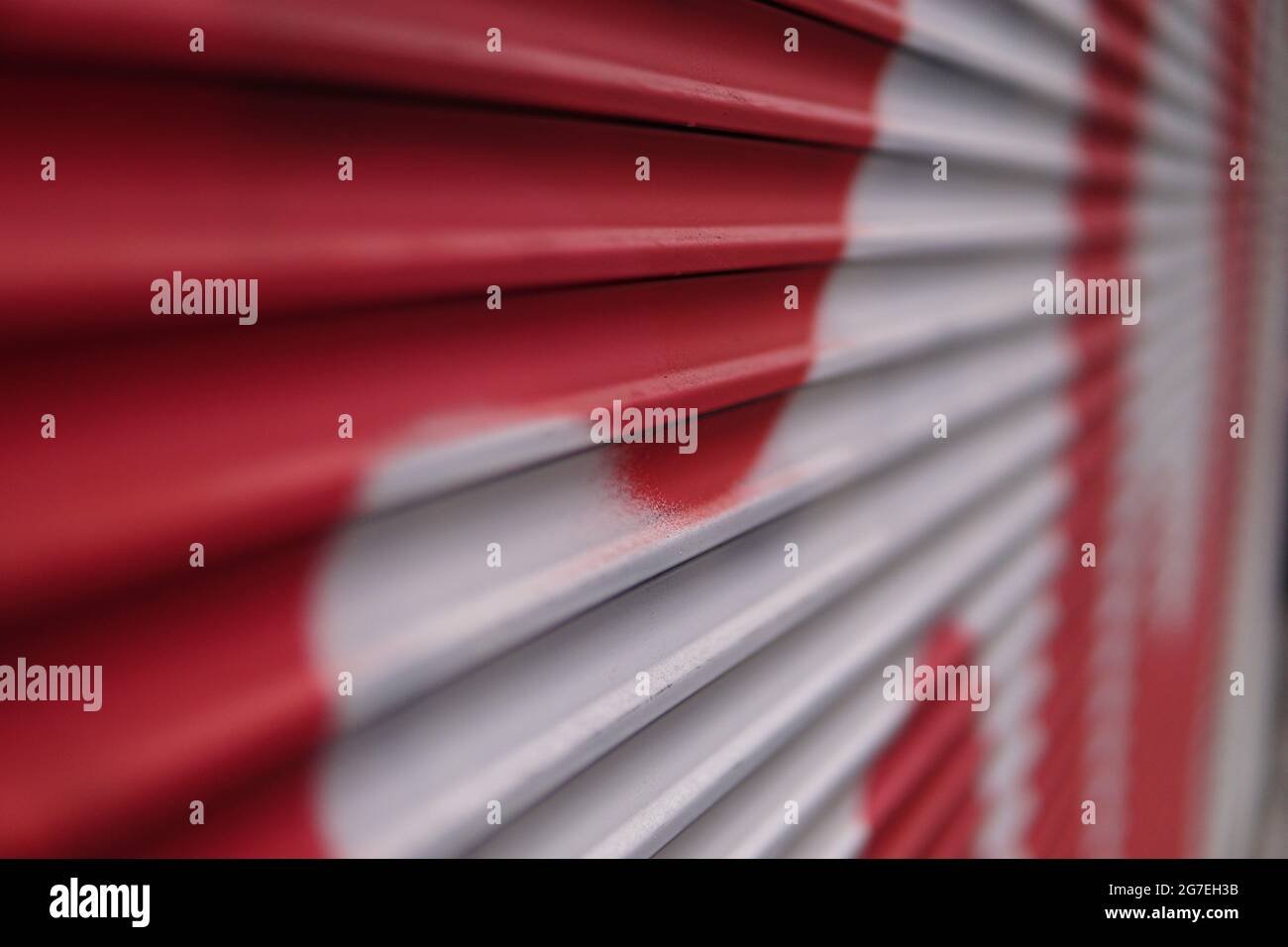 Closeup shot of an abstract red and white graffiti on a folding metal gate outdoors Stock Photo