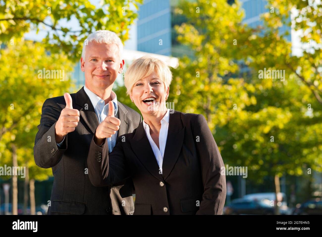 Business people - mature or senior - standing in a park outdoors in front of a office building Stock Photo