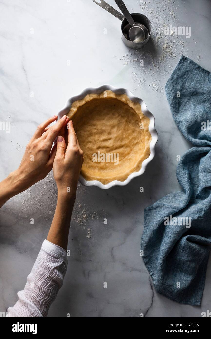A person pressing pastry into a dish Stock Photo