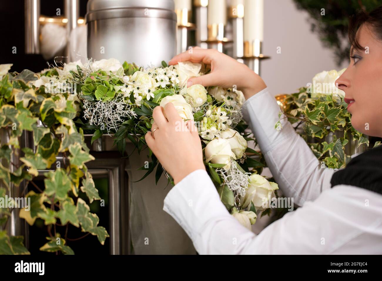 death and dolor  - mortician on funeral with urn preparing the flowers Stock Photo