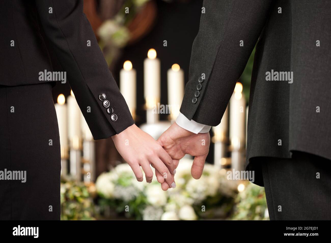 Religion, death and dolor  - couple at funeral holding hands consoling each other in view of the loss Stock Photo