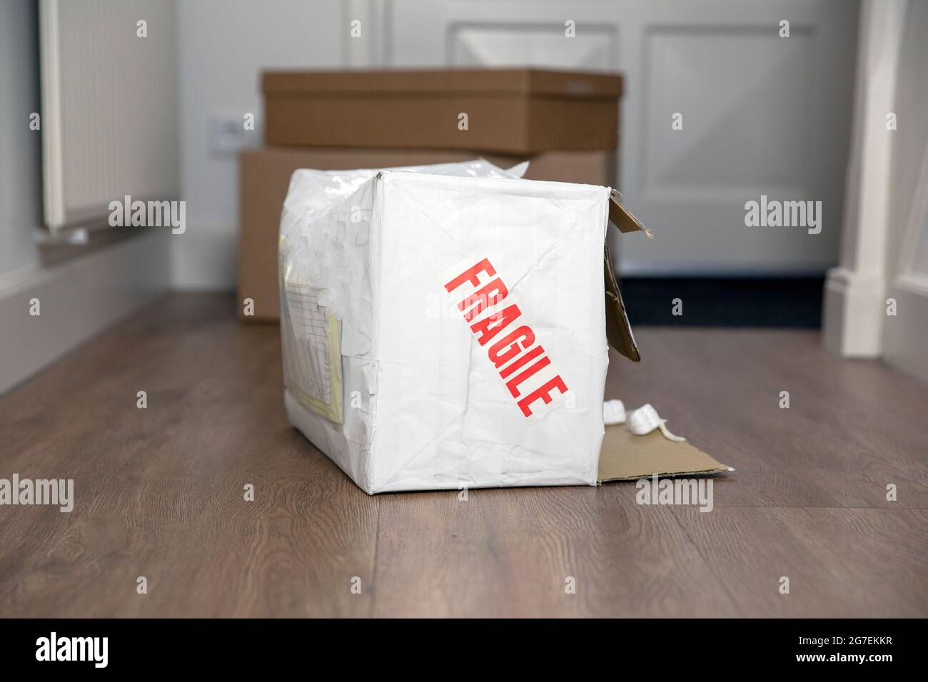 Beat up damaged delivery box with fragile sticker, broken deliverd cardboard packaging at home Stock Photo