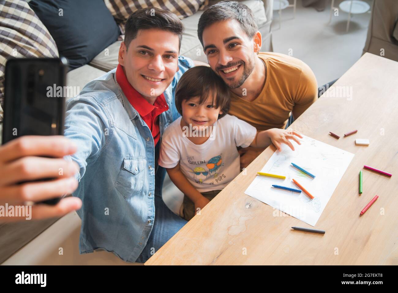 Gay couple taking a selfie with their son at home. Stock Photo