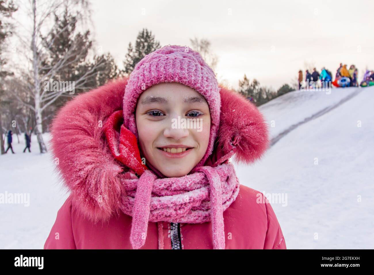 Girl with frost on the eyelashes on the background of a snow hill in the coldest in the world northern residential village Oymyakon. Stock Photo