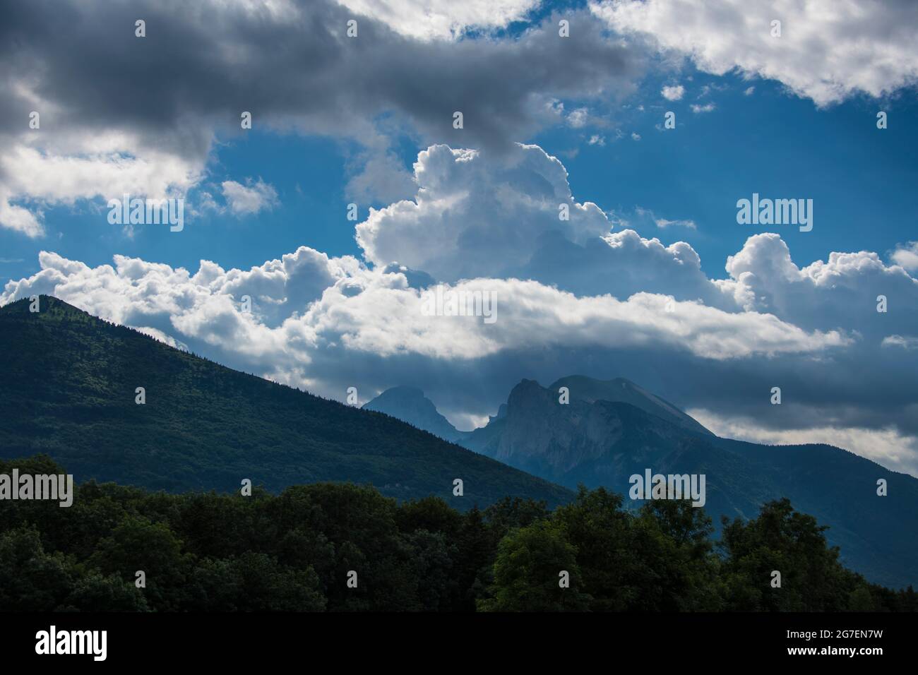 Mountain landscape with mountain peaks, forest and the cloudy blue sky, by stormy weather Stock Photo