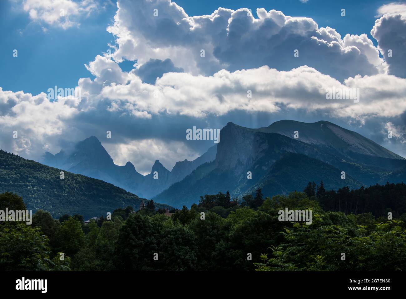 Mountain landscape with mountain peaks, forest and the cloudy blue sky, by stormy weather Stock Photo