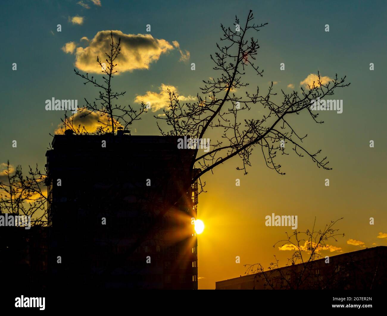 The rays of the setting sun between the houses of a large industrial city. Stock Photo