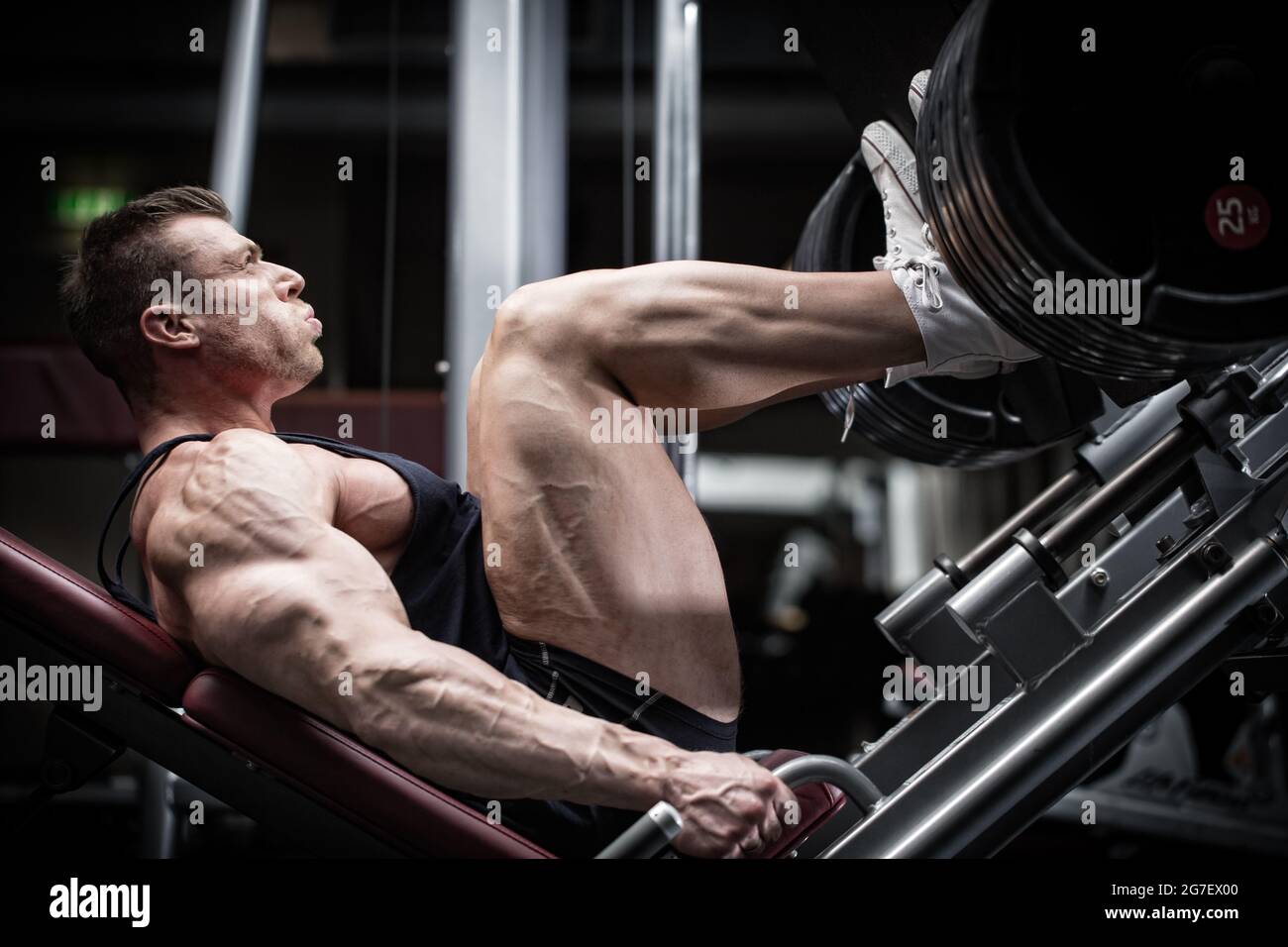 Man in gym training at leg press to define his upper leg muscles Stock Photo