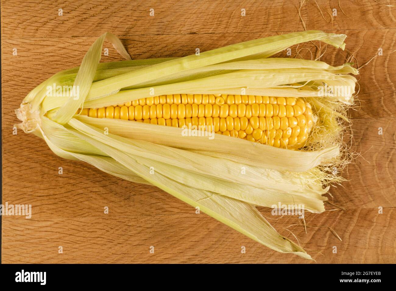 Kachan of young corn, in husks, on a wooden board Stock Photo