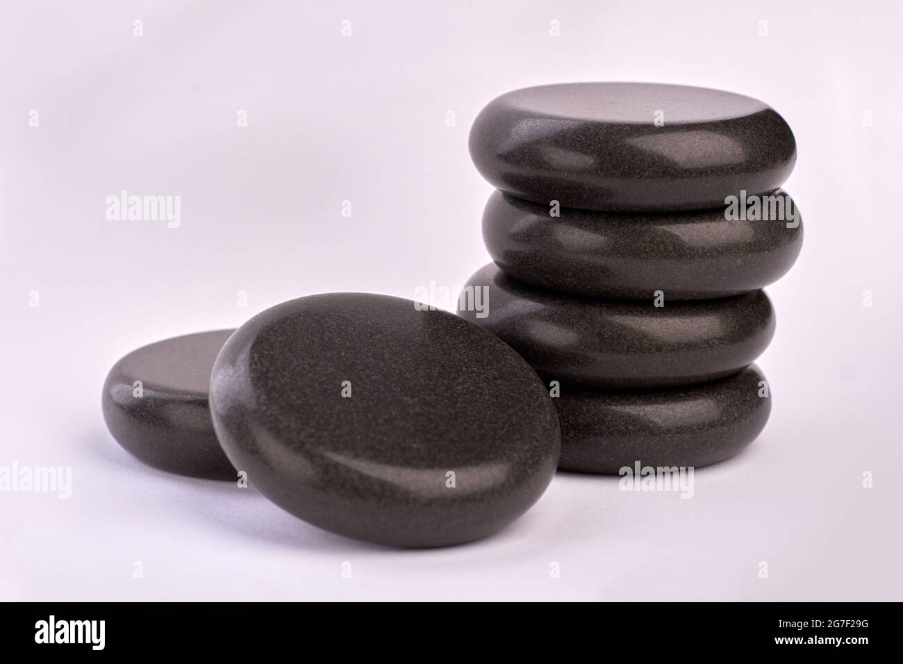 Polished black stones for spa treatment therapy on white background