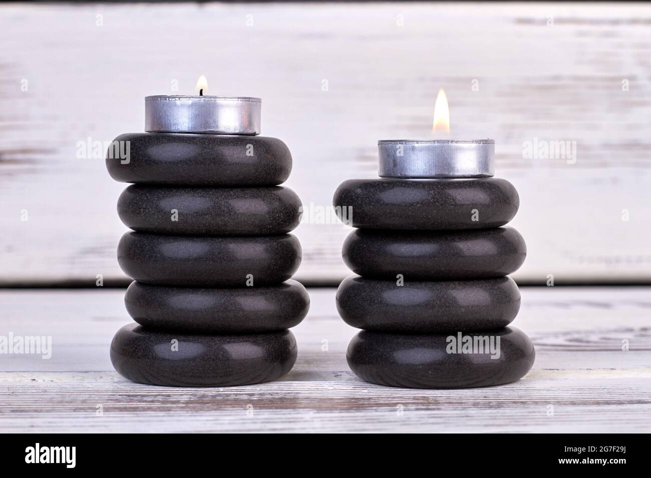 Stacks of black stones with candles for spa therapy. Stock Photo