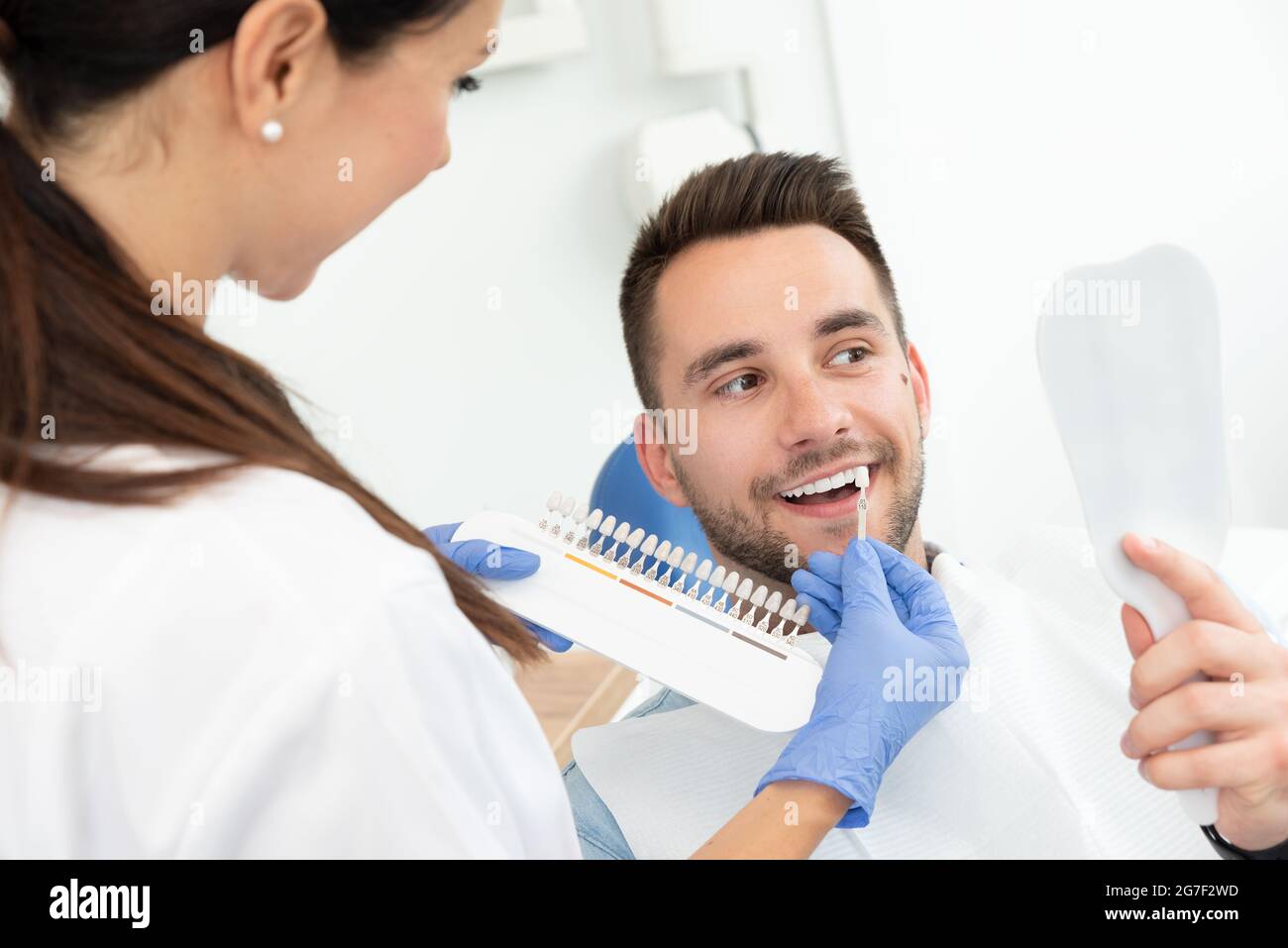 Handsome young man in stomatology clinic with female dentist. Healthy teeth whitening. Stock Photo
