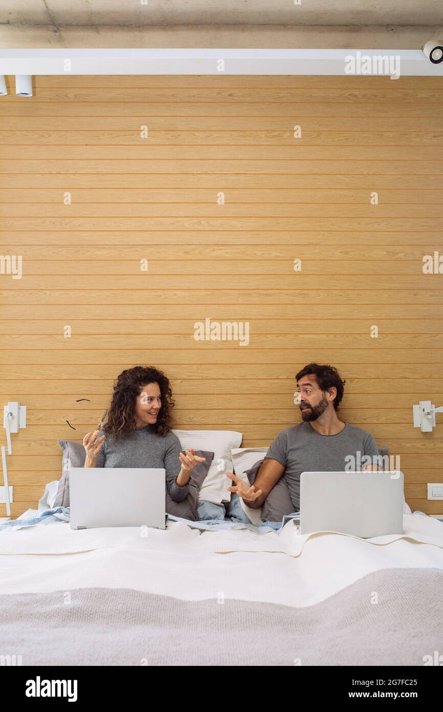 Couple in a double bed king size each with their notebook Stock Photo