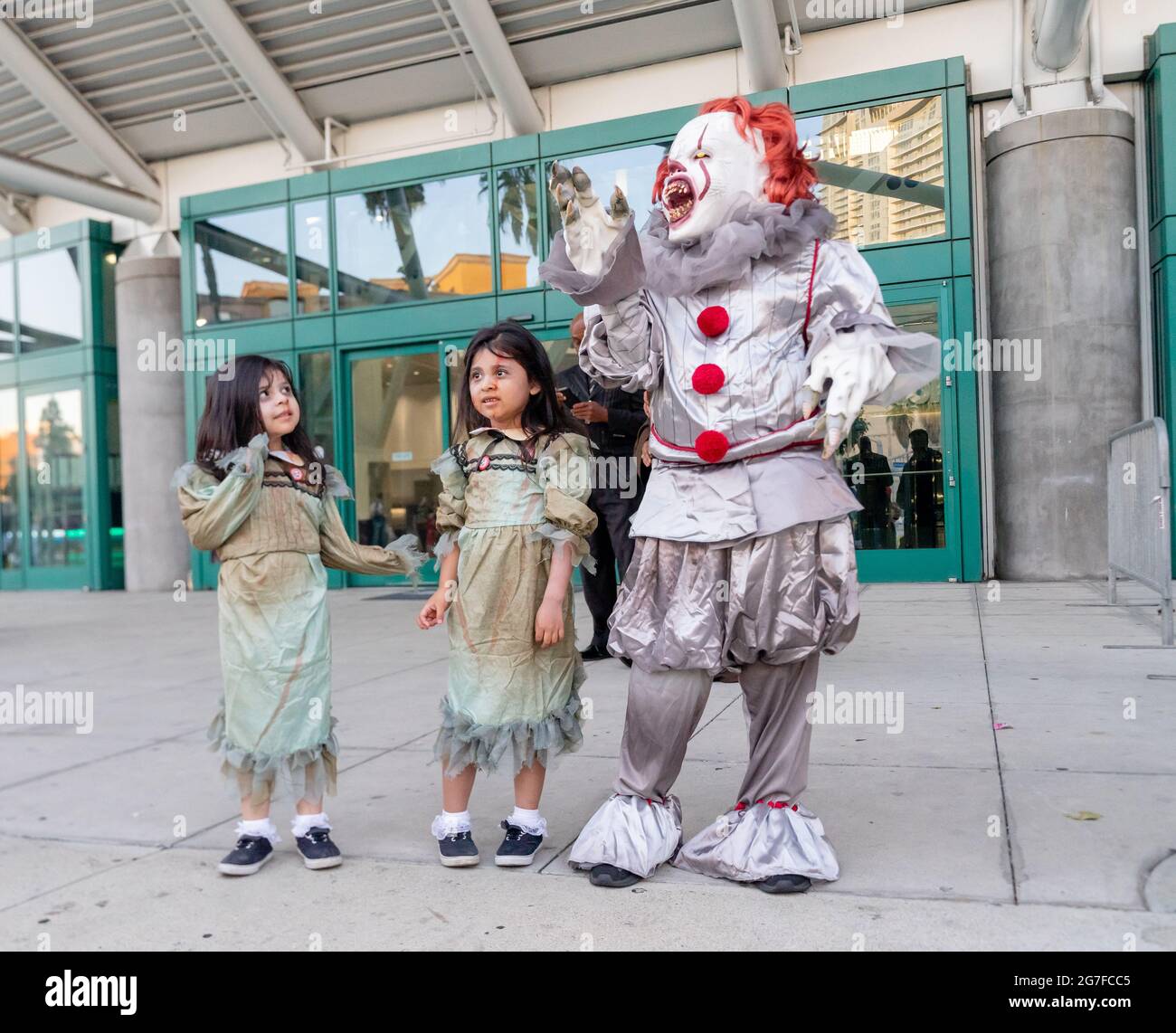 An attendee dressed as Pennywise the Dancing Clown poses with two little girls in costumes at Comic Con in Los Angeles, CA, United States Stock Photo