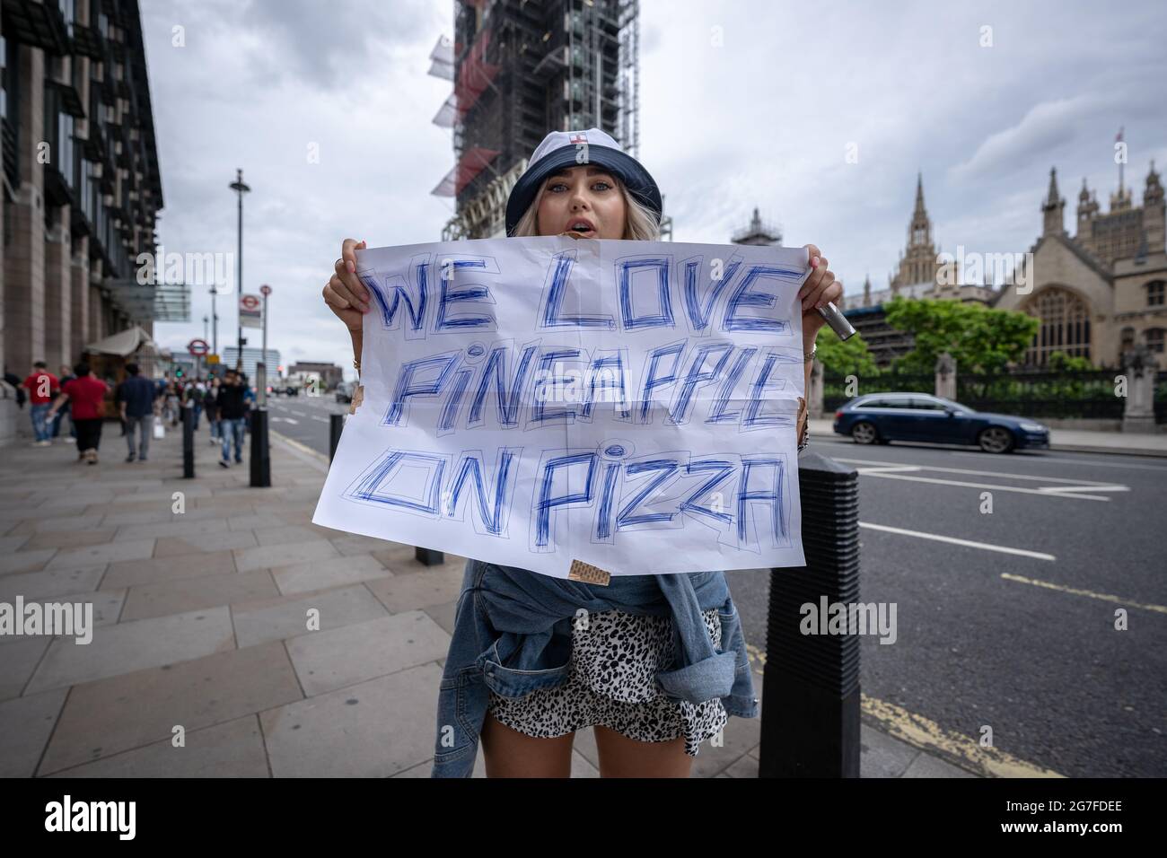 Euro 2020: 'We Love Pineapple on Pizza' sign as football fans crowd into central London ahead of England vs Italy match finals. London, UK. Stock Photo