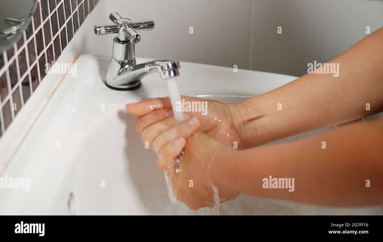 Closeup young woman hands using soap and washing hands under the water ...