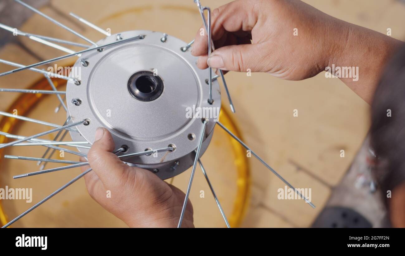 Technician man working motorcycle wheel has spokes weave up on mechanic