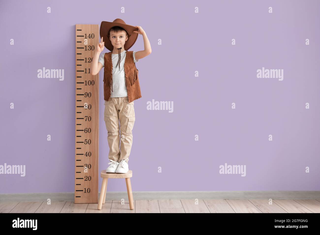 Little boy measuring height near color wall Stock Photo